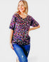 Woman wearing a colorful patterned top and blue jeans on a white background