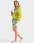 Woman wearing a bright yellow jacket and denim shorts on a white background