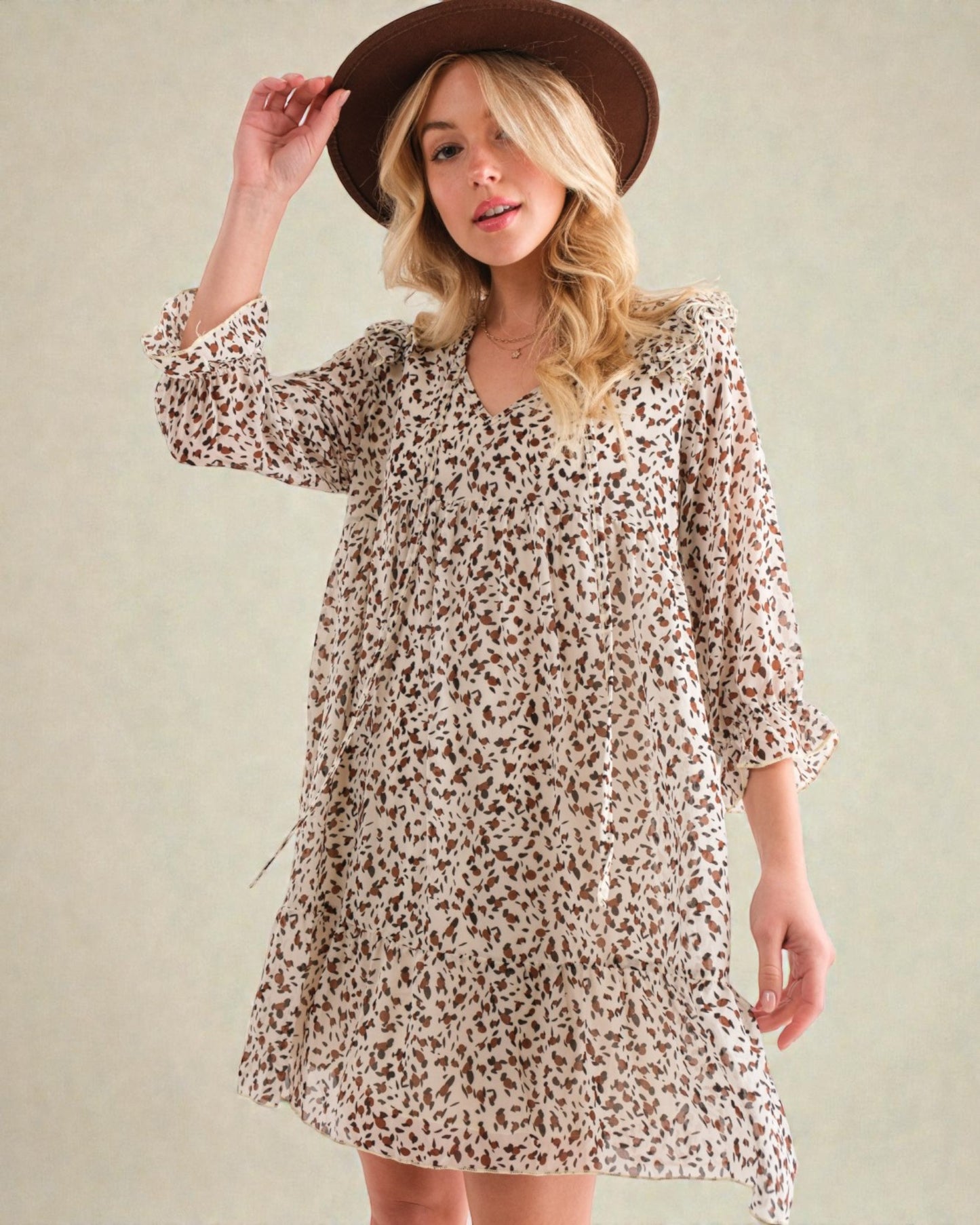 Woman wearing a floral dress and brown hat against a plain background