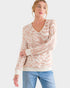 Woman wearing a beige and white leopard print sweater with blue jeans on a white background