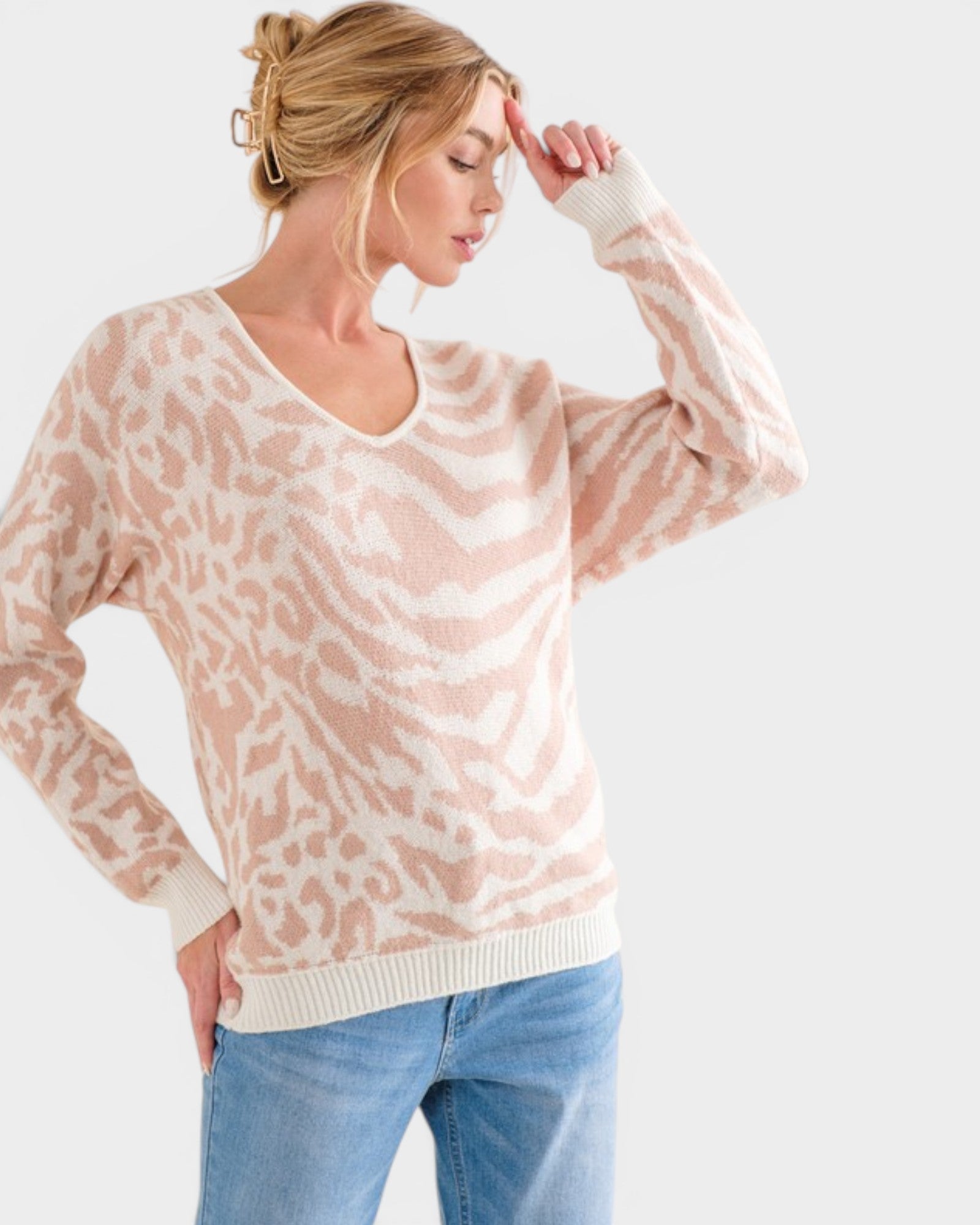 Woman wearing a light pink sweater with a subtle pattern on a white background