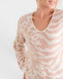 Woman wearing a beige and white patterned sweater on a plain background