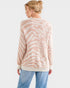 Woman wearing a patterned sweater and jeans on a white background