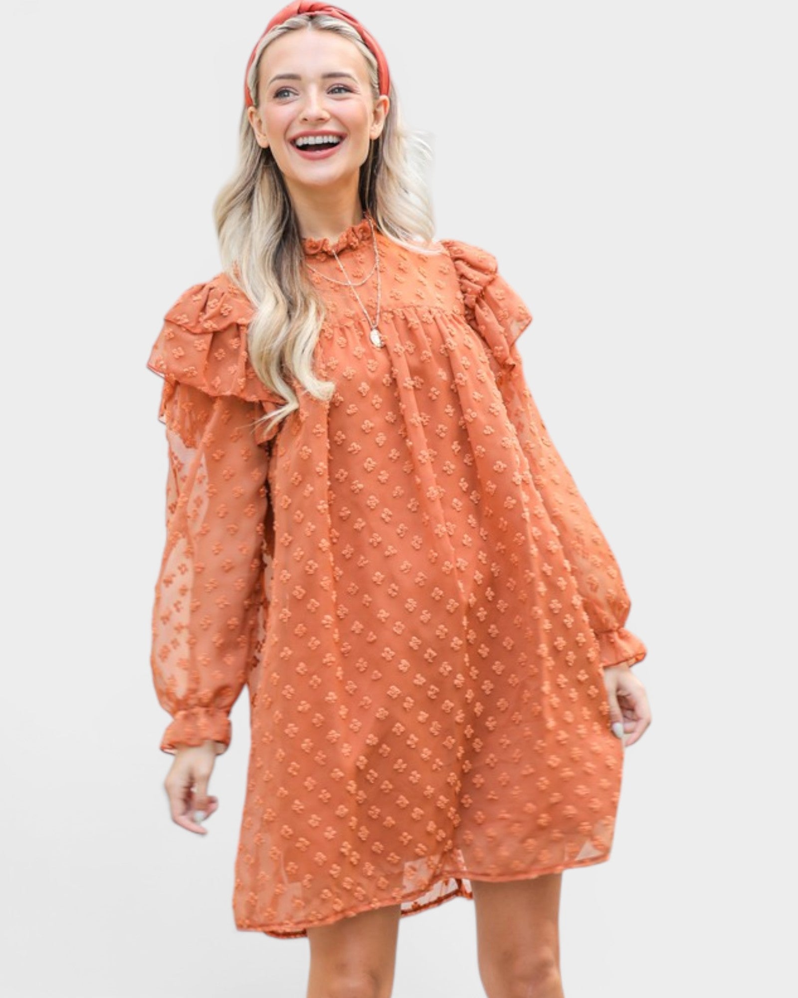 Woman wearing a rust-colored dress with long sleeves and a red headband on a white background