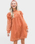 Woman wearing a rust-colored dress with long sleeves and a red headband on a white background