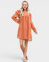 Woman wearing an orange dress with long sleeves on a white background
