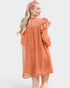 Woman wearing a rust-colored dress with ruffled sleeves on a white background