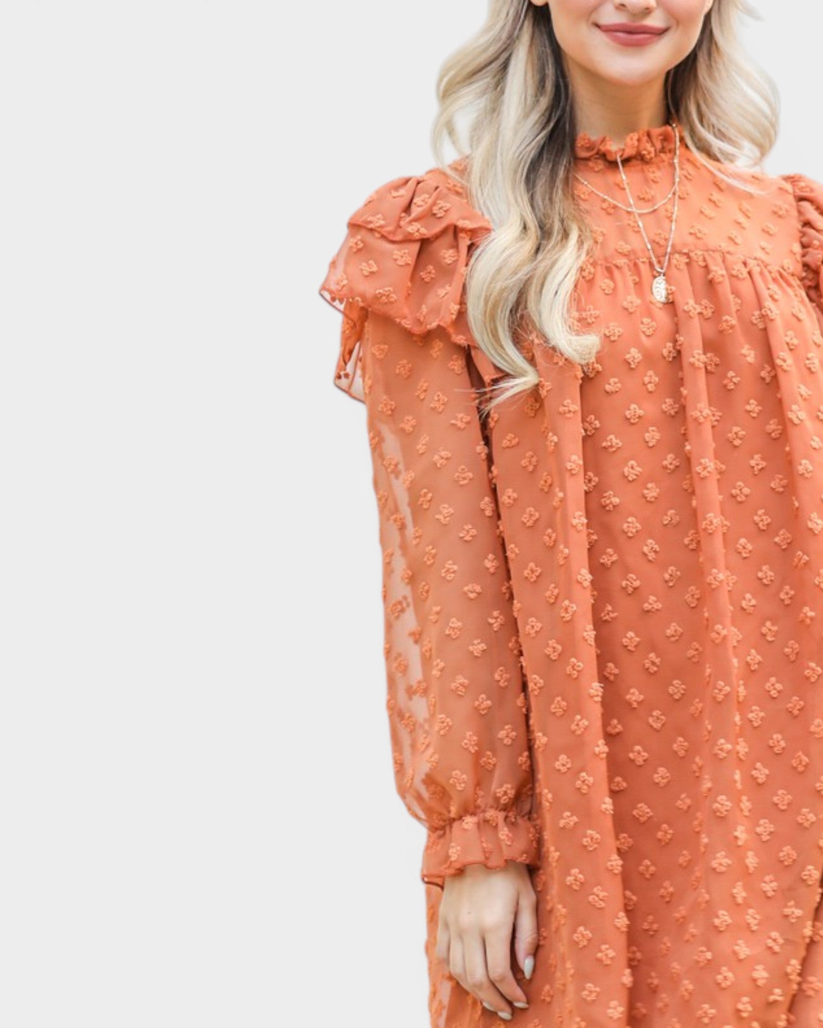 Woman wearing an orange dress with ruffled sleeves against a white background