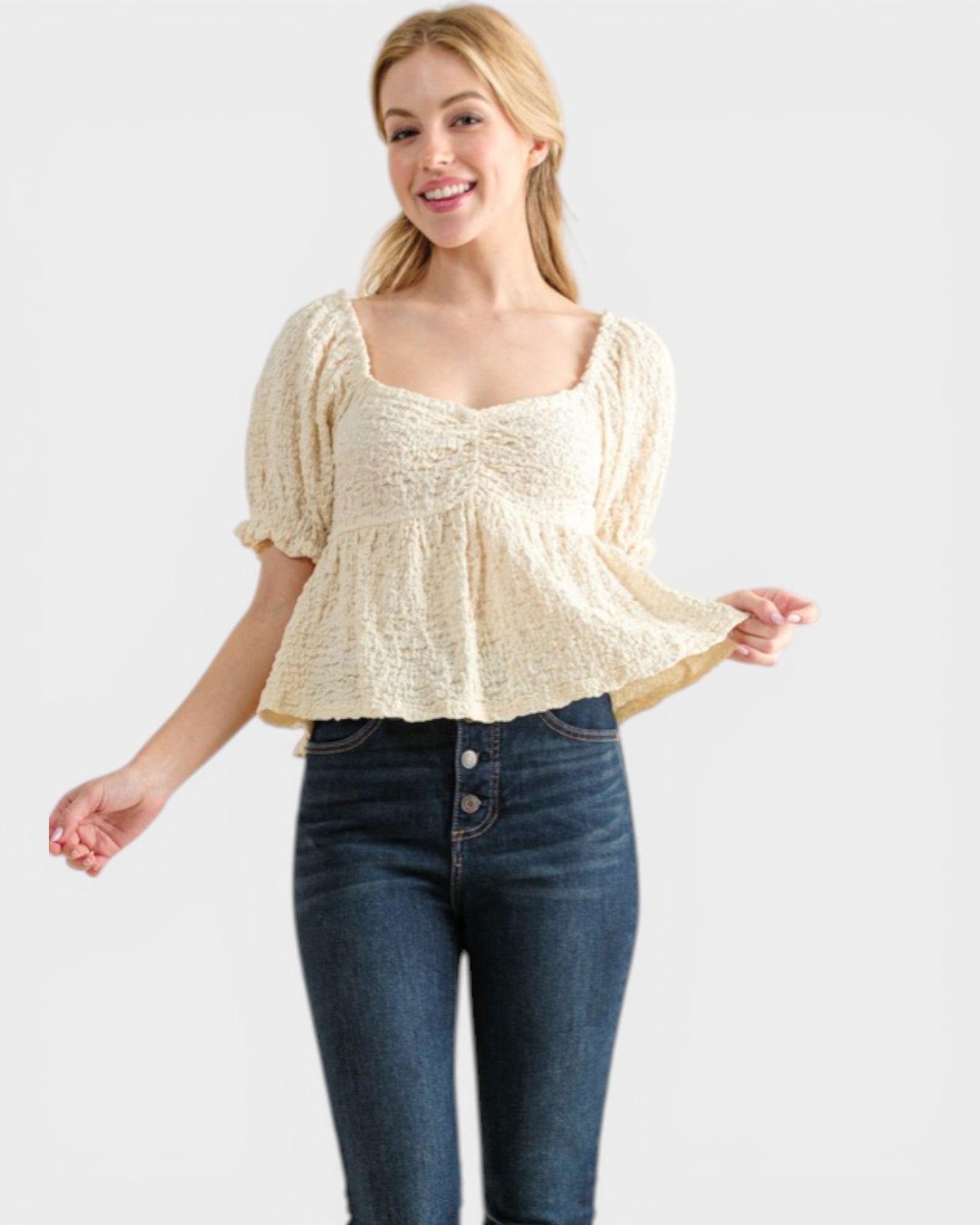 Woman wearing a beige top and blue jeans on a white background