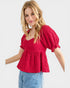 Woman wearing a red blouse with puff sleeves on a white background