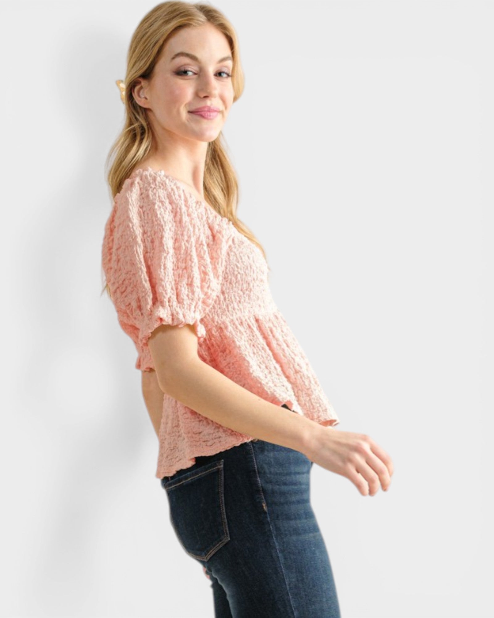 Woman wearing a pink lace top and blue jeans on a white background