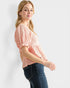 Woman wearing a pink lace top and blue jeans on a white background