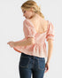 Woman wearing a pink blouse and blue jeans on a white background