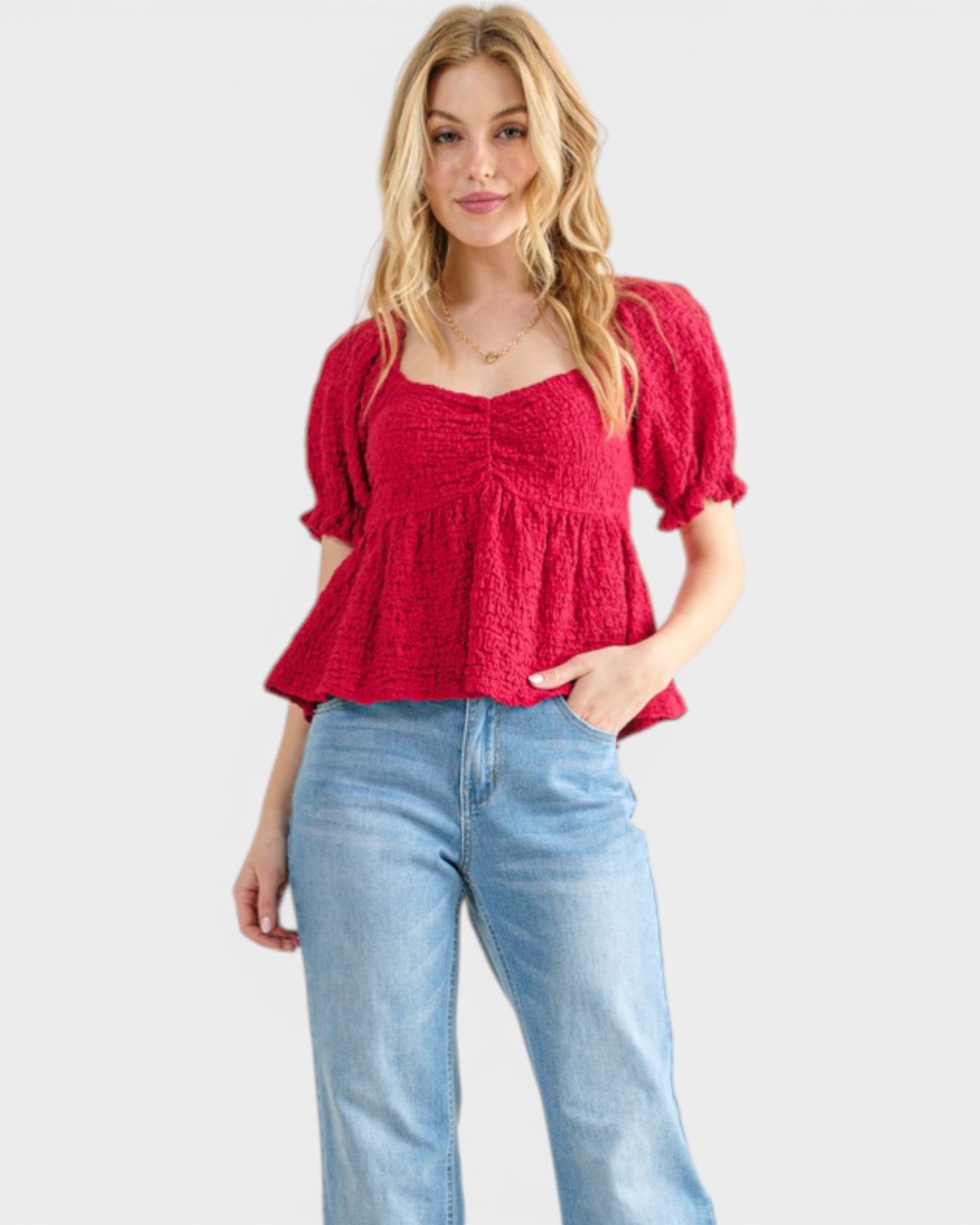 Woman wearing a red top and blue jeans on a white background
