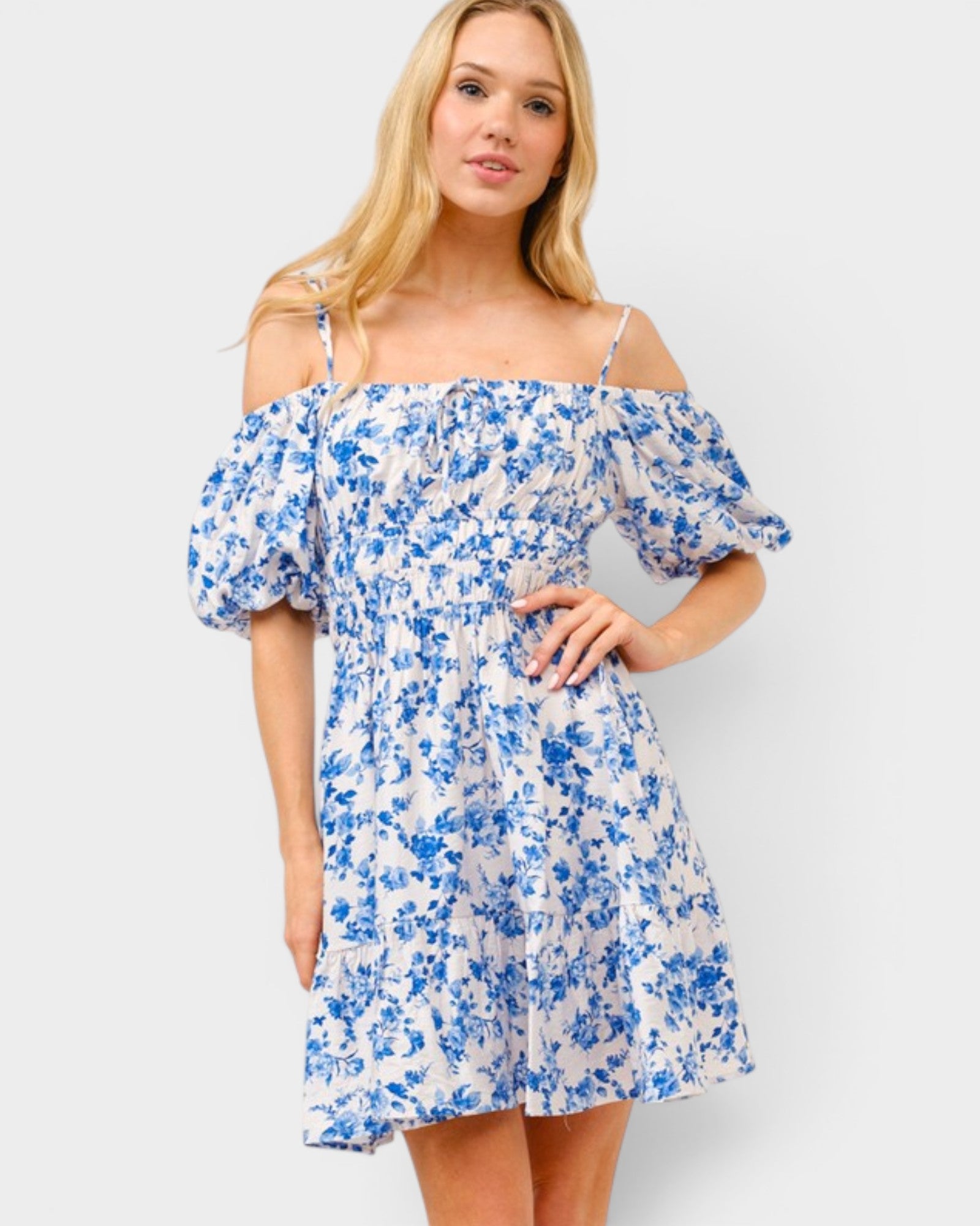 Woman wearing a blue floral off-shoulder dress on a white background