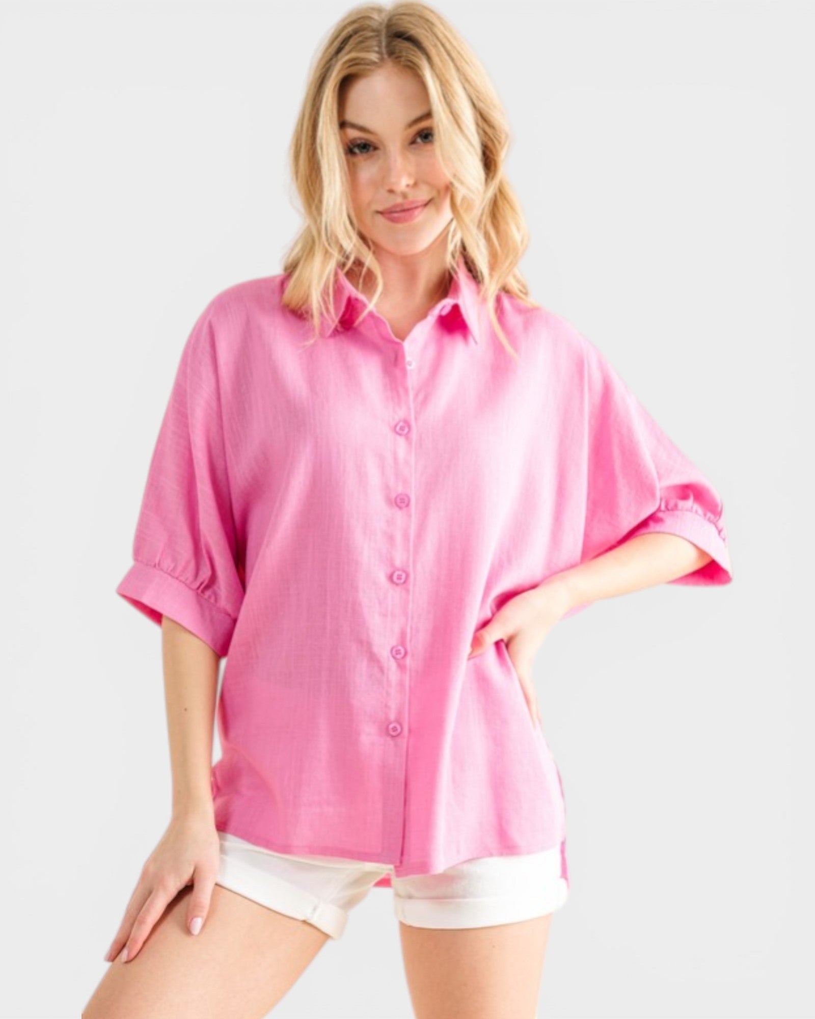 Woman wearing a pink shirt with rolled-up sleeves on a white background