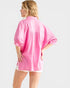Woman wearing a pink oversized shirt on a light gray background