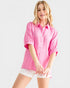 Woman wearing a pink shirt and white shorts on a light gray background