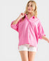 Woman wearing a pink shirt and white shorts on a light gray background