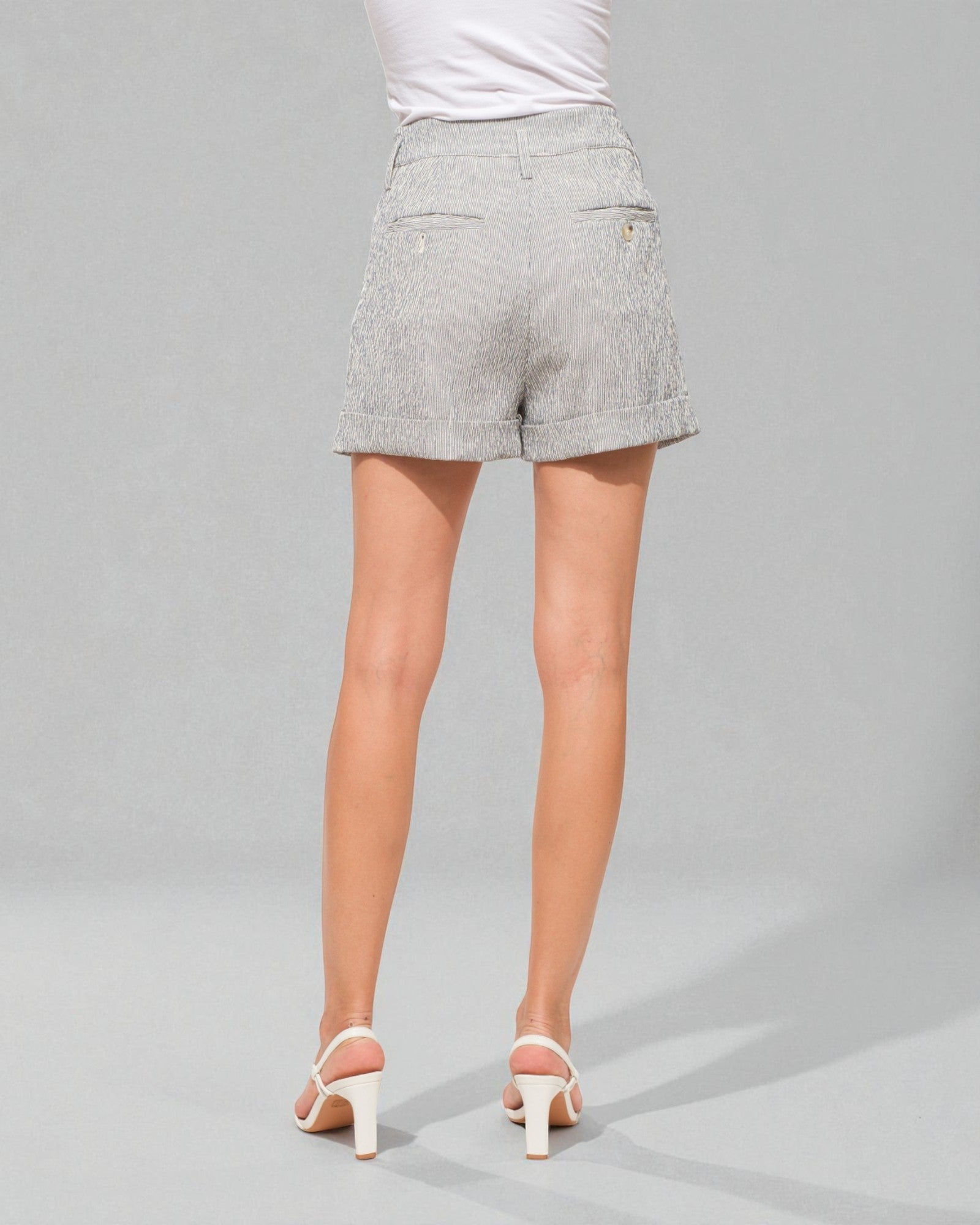 Person wearing light gray shorts on a gray background