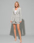 Woman wearing a gray blazer and skirt set against a gray background