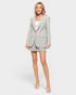 Woman wearing a gray blazer and shorts set on a white background