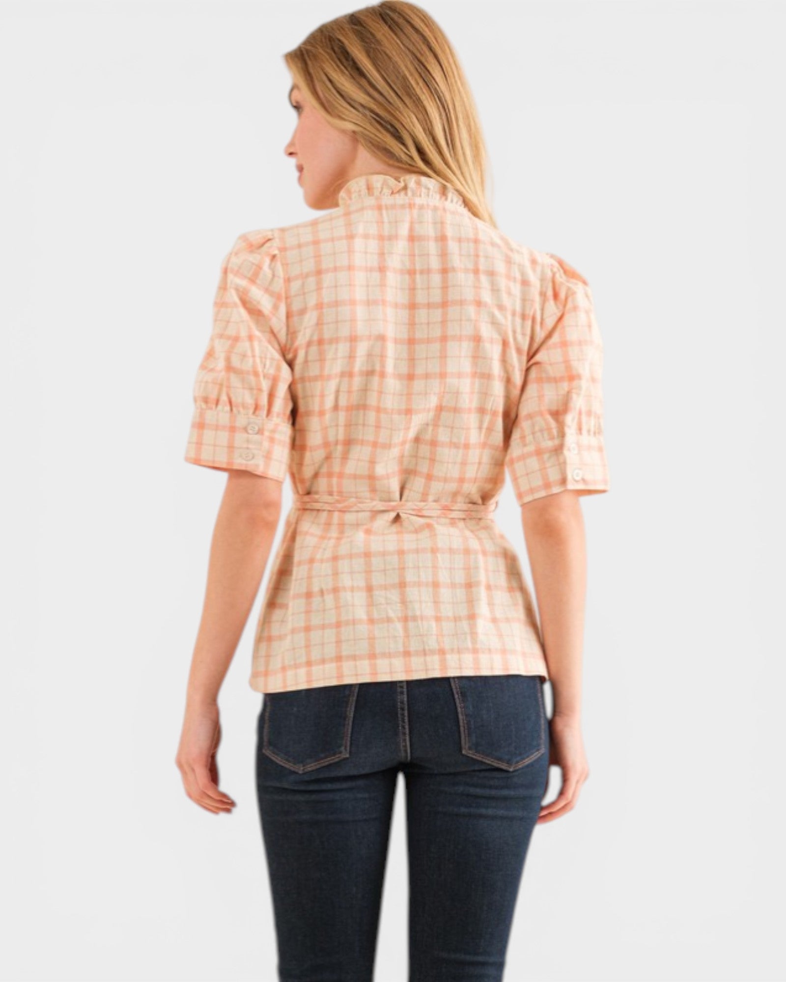 Woman wearing a plaid shirt and dark jeans on a white background