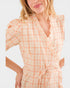 Woman wearing a peach and white checkered dress on a light background