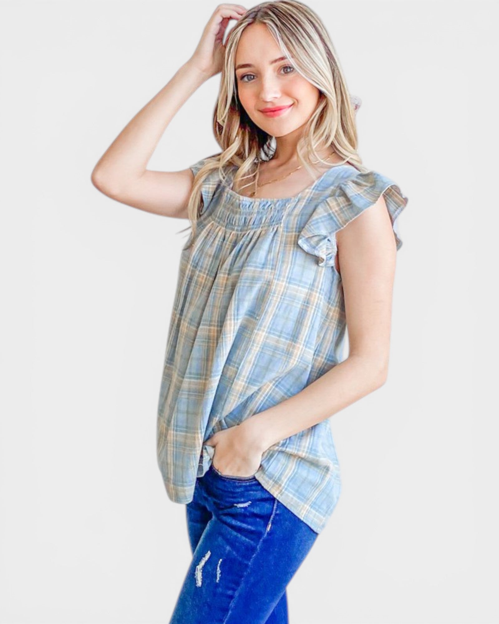 Woman wearing a blue plaid top and blue jeans on a white background