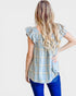 Woman wearing a plaid shirt with ruffled sleeves on a white background