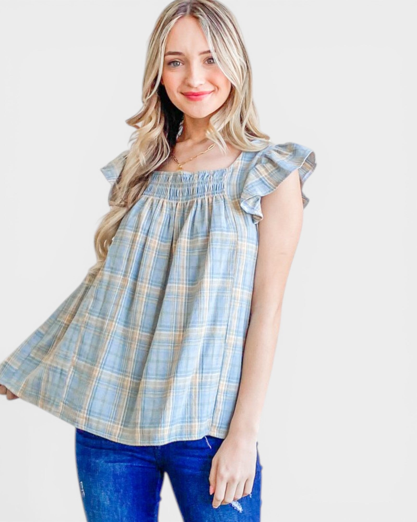 Woman wearing a blue plaid top with ruffled sleeves on a white background
