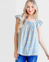Woman wearing a blue plaid top with ruffled sleeves on a white background