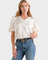 Woman wearing a white blouse with puff sleeves and blue jeans on a white background