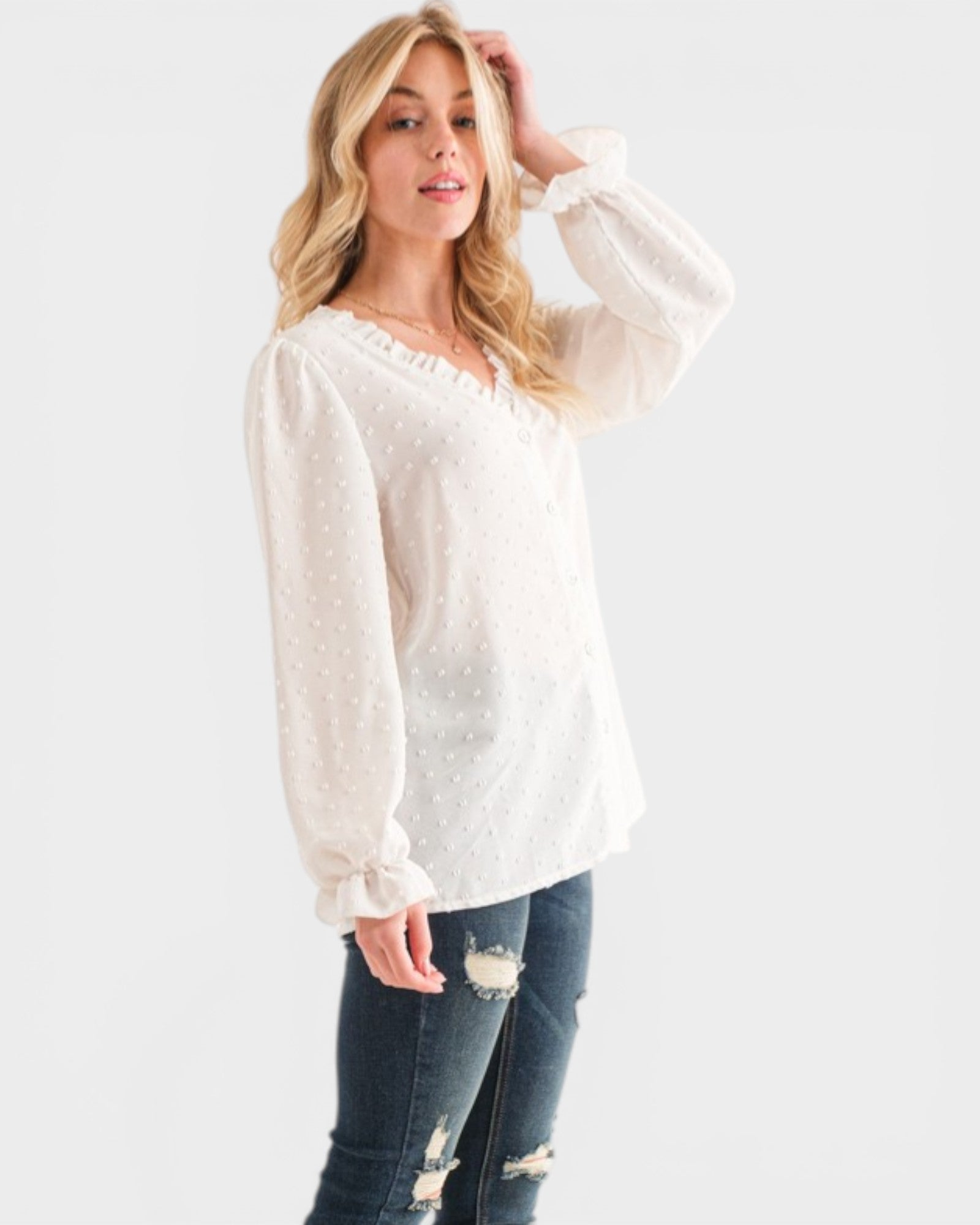 Woman wearing a white blouse with long sleeves and blue jeans on a white background