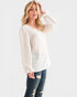 Woman wearing a white blouse with long sleeves and blue jeans on a white background