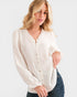 Woman wearing a white blouse with a subtle pattern on a plain background