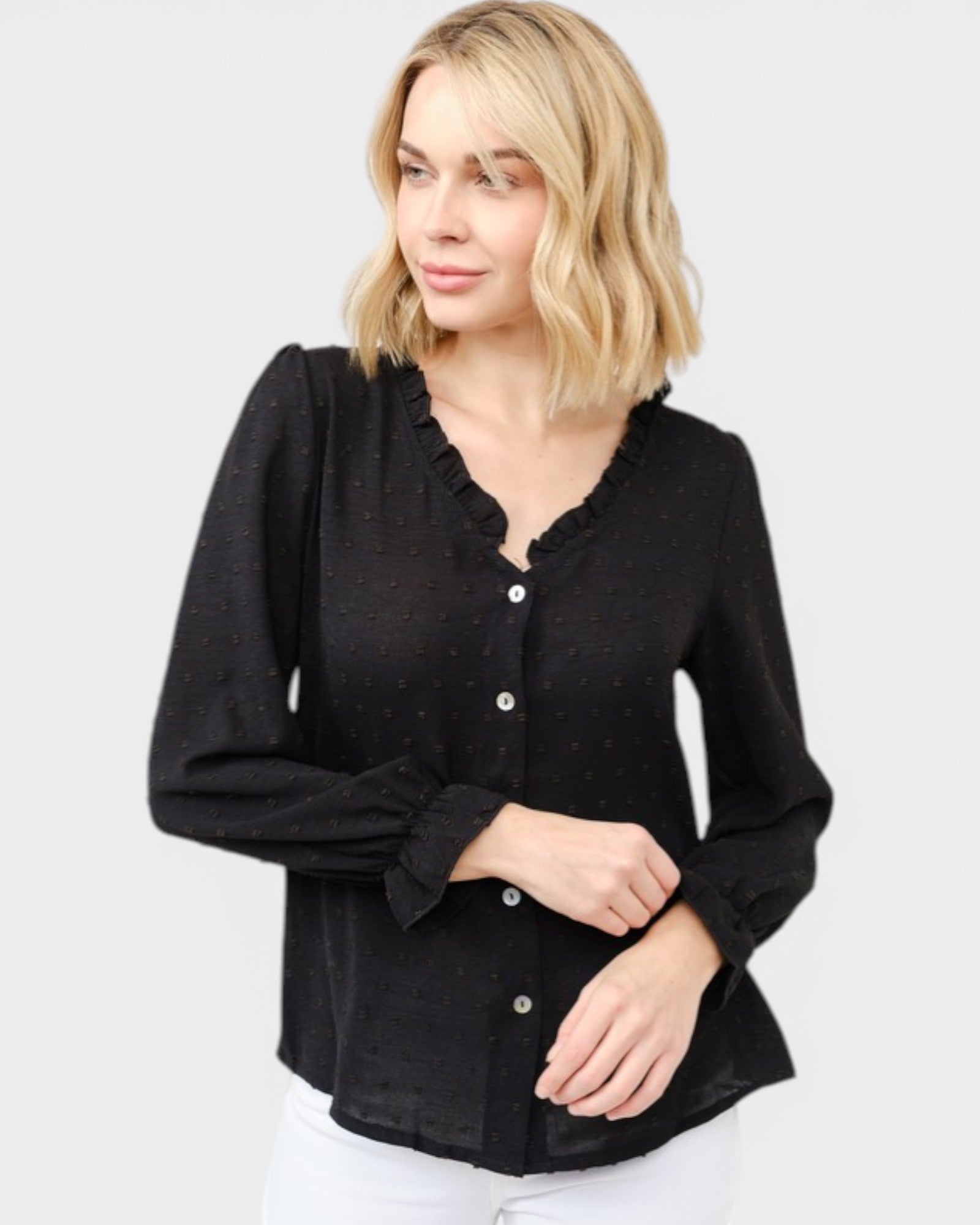 Woman wearing a black long-sleeve top with buttons on a white background