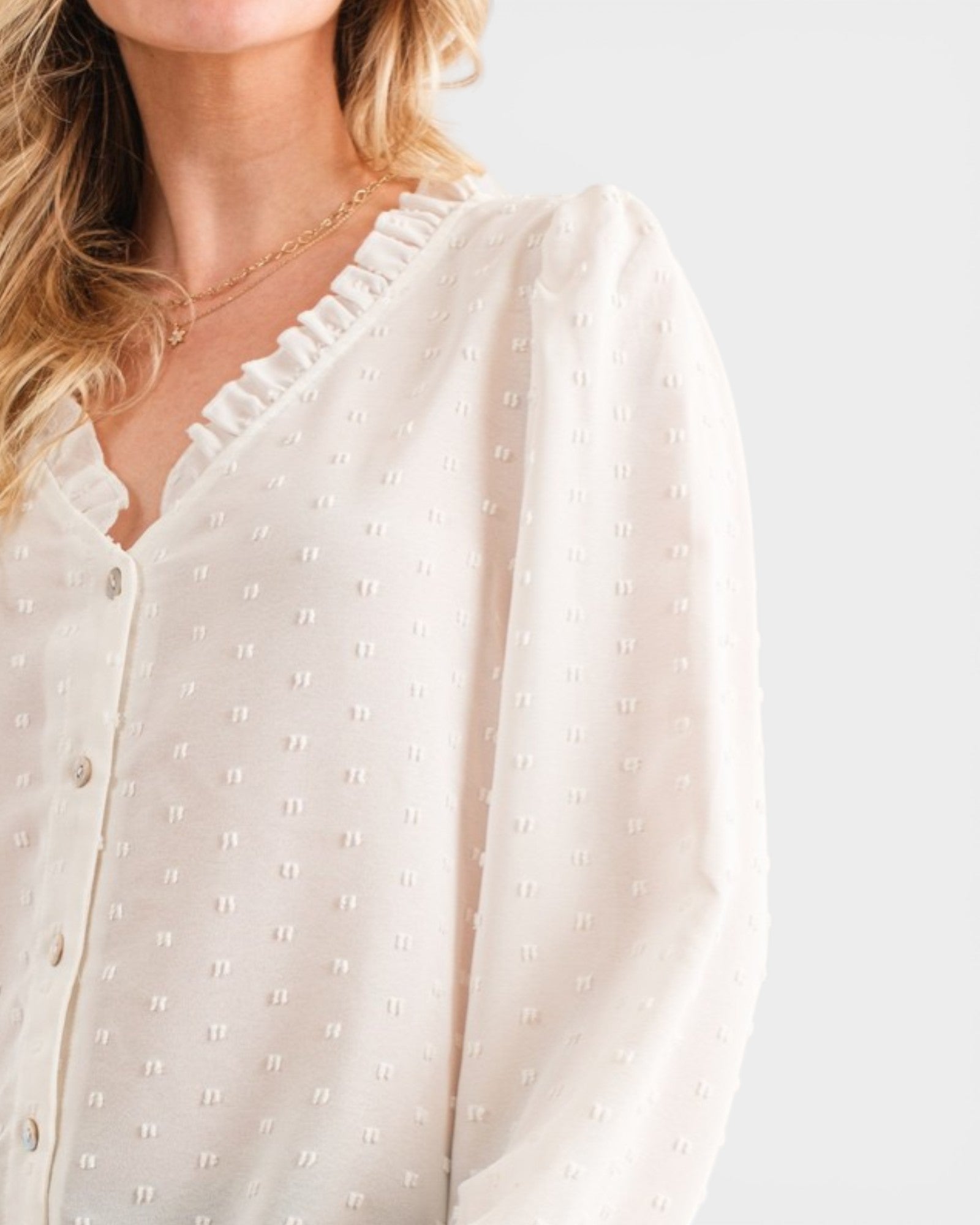 Woman wearing a white blouse with a subtle pattern on a light gray background