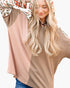 A woman wearing a color-blocked long-sleeve top with a dusty pink left side, a tan right side, and a patterned hood, set against a plain white background.