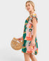 Woman wearing a colorful dress holding a wooden handbag on a white background