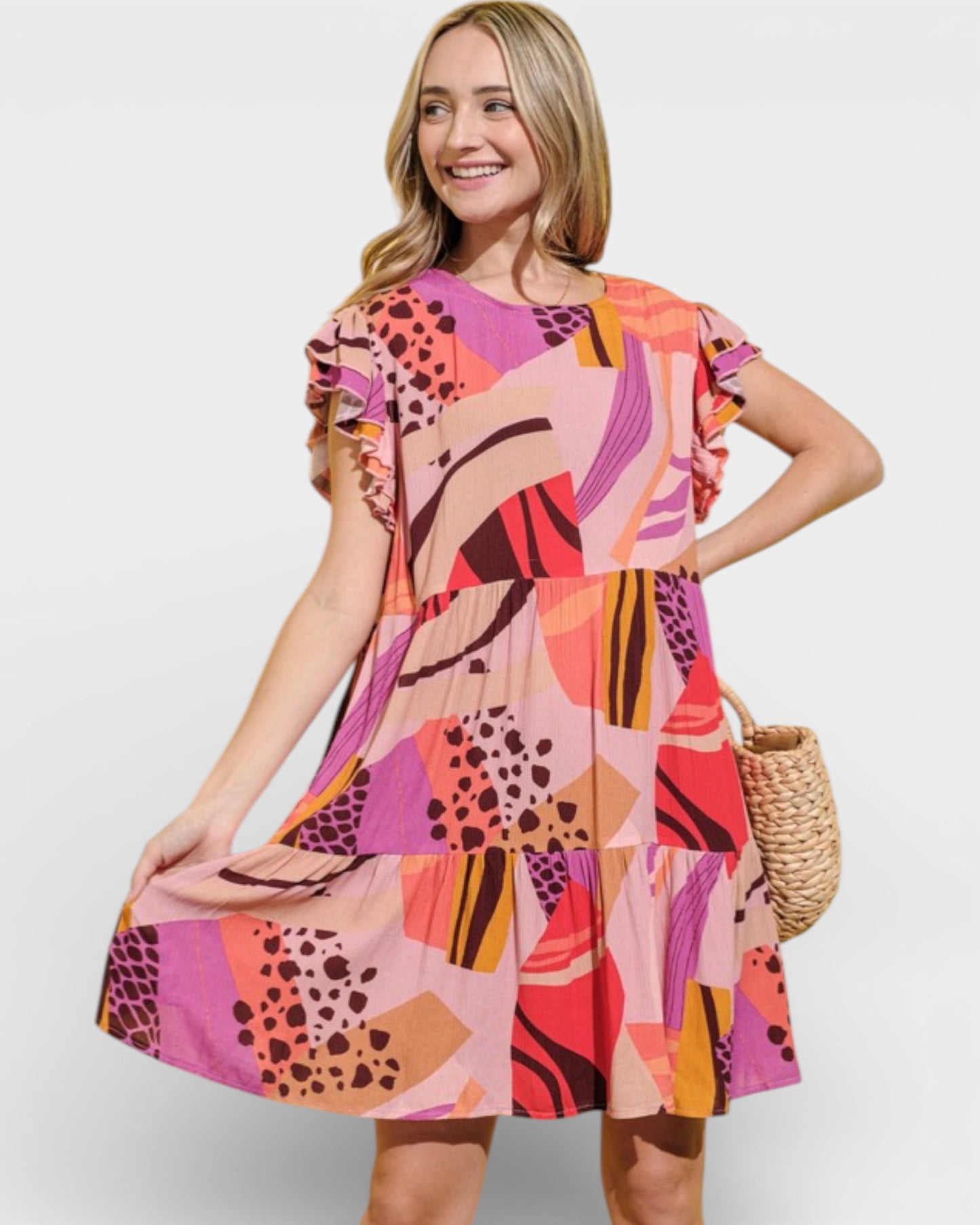Woman wearing a colorful patterned dress holding a woven bag on a white background