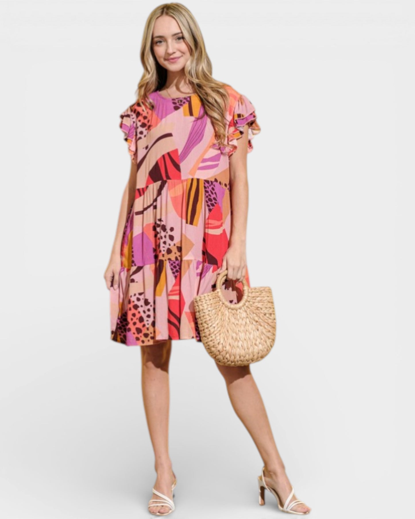 Woman wearing a colorful dress holding a straw bag on a white background
