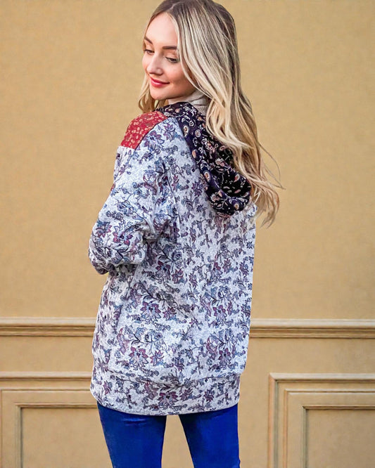 Woman wearing a floral jacket with a red patch on a beige wall background