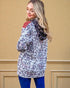 Woman wearing a floral jacket with a red patch on a beige wall background