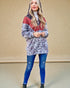 Woman wearing a patterned hoodie and blue jeans against a beige background