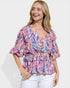 Woman wearing a colorful patterned blouse against a white background
