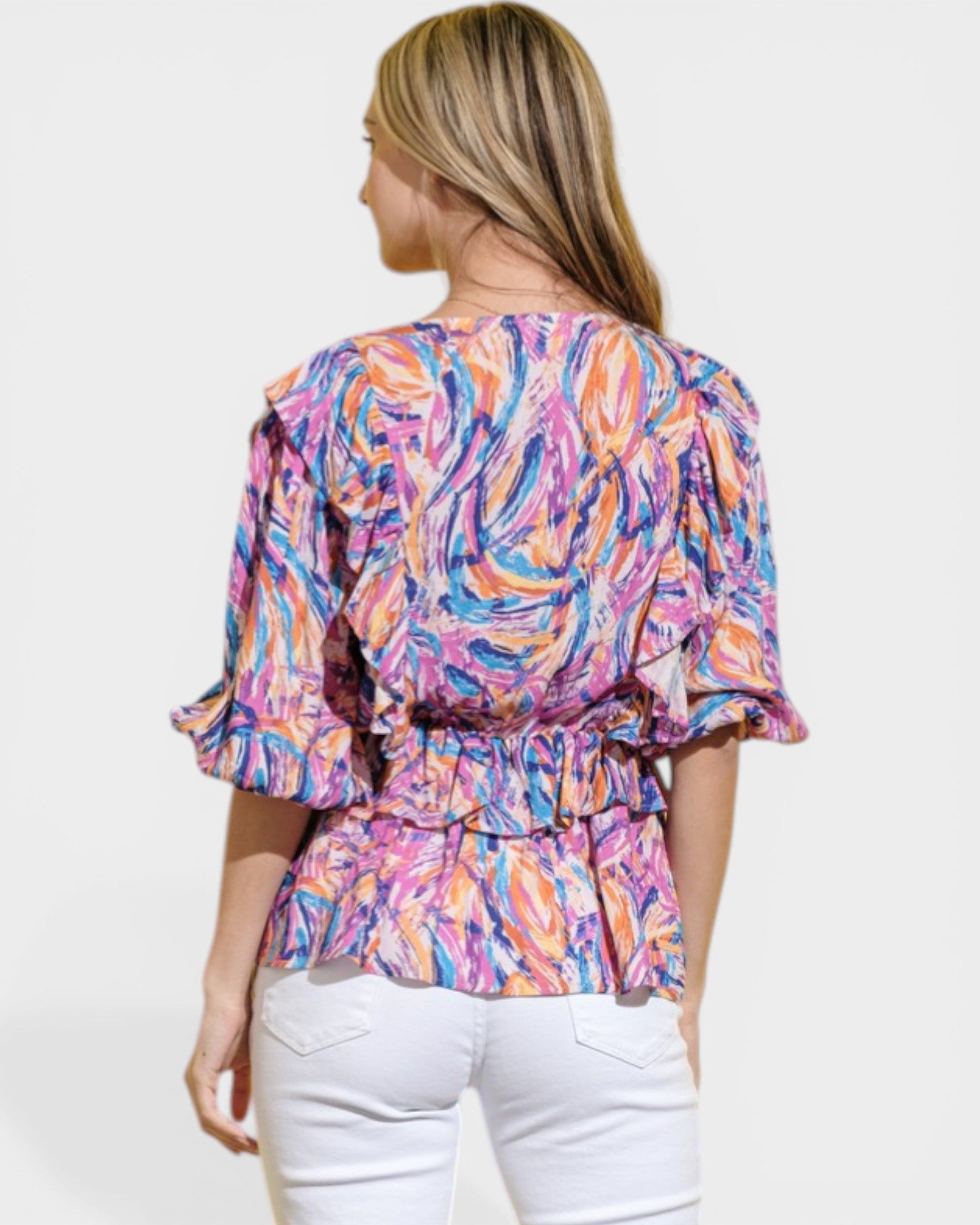 Woman wearing a colorful patterned top with a plain background