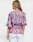Woman wearing a colorful patterned top with a plain background