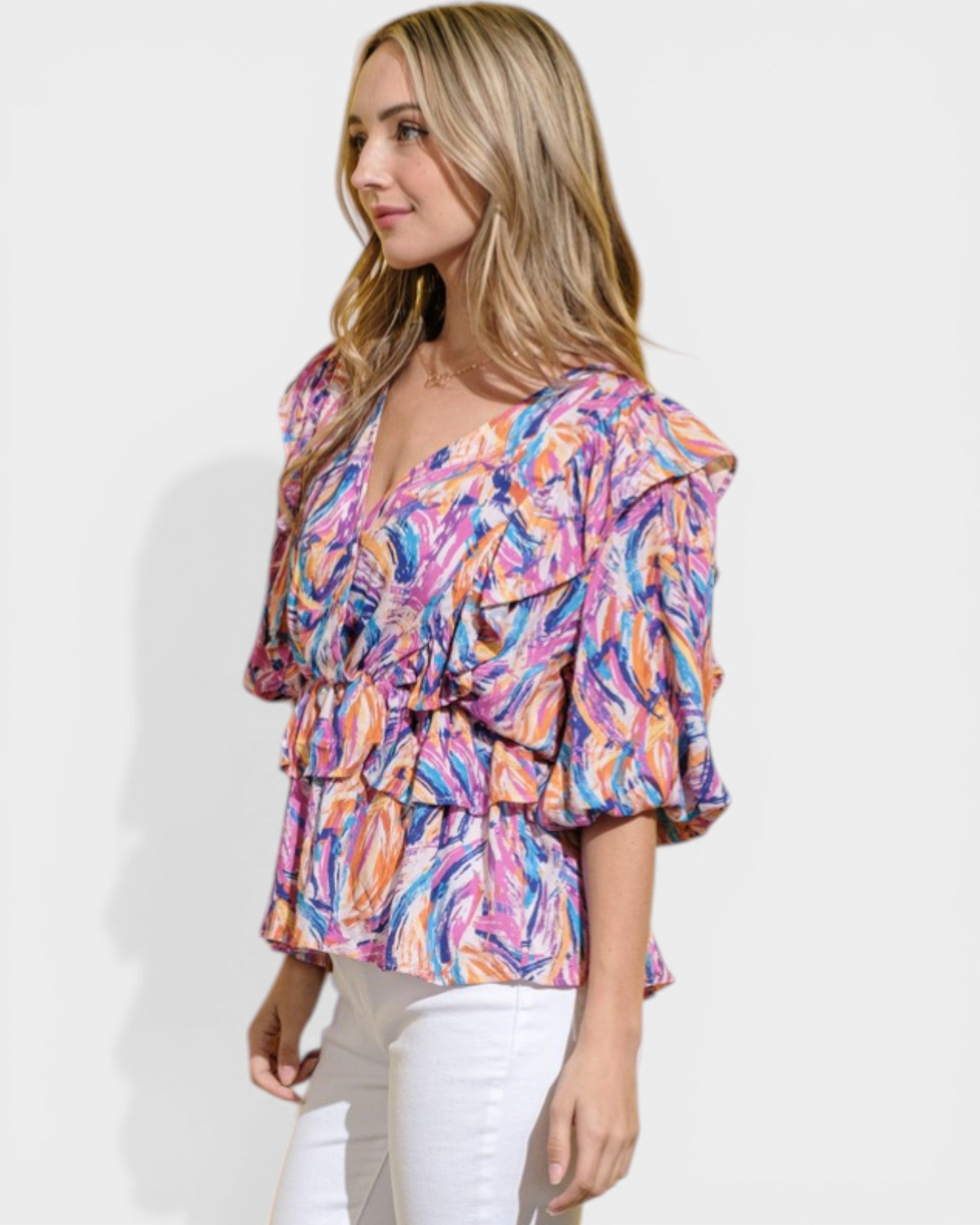 Woman wearing a colorful patterned blouse against a white background