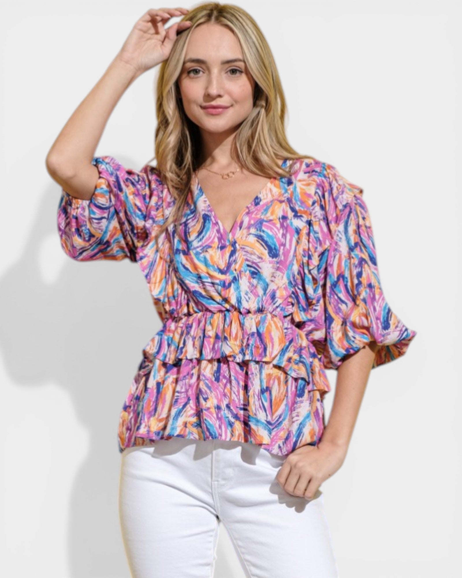Woman wearing a colorful patterned top against a white background
